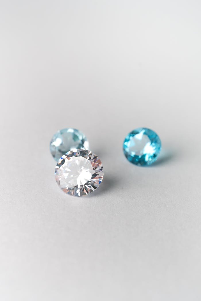 Close-up of sparkling blue and white gemstones on a smooth white surface, showcasing brilliance.