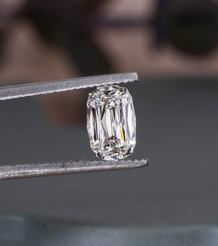 Close-up of a sparkling lab-grown diamond held by tweezers, showcasing intricate cuts.